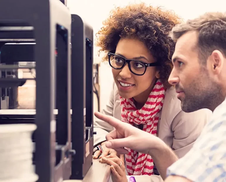 Two people looking at a 3d printer.